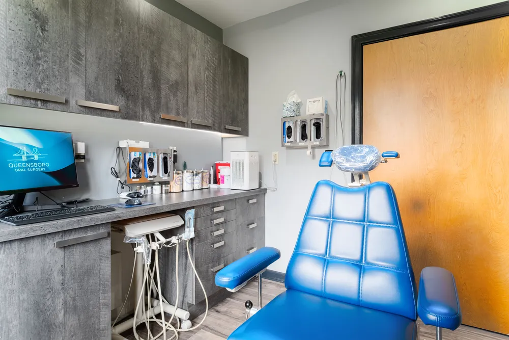 Treatment room with a blue patient chair at Queensboro Oral Surgery